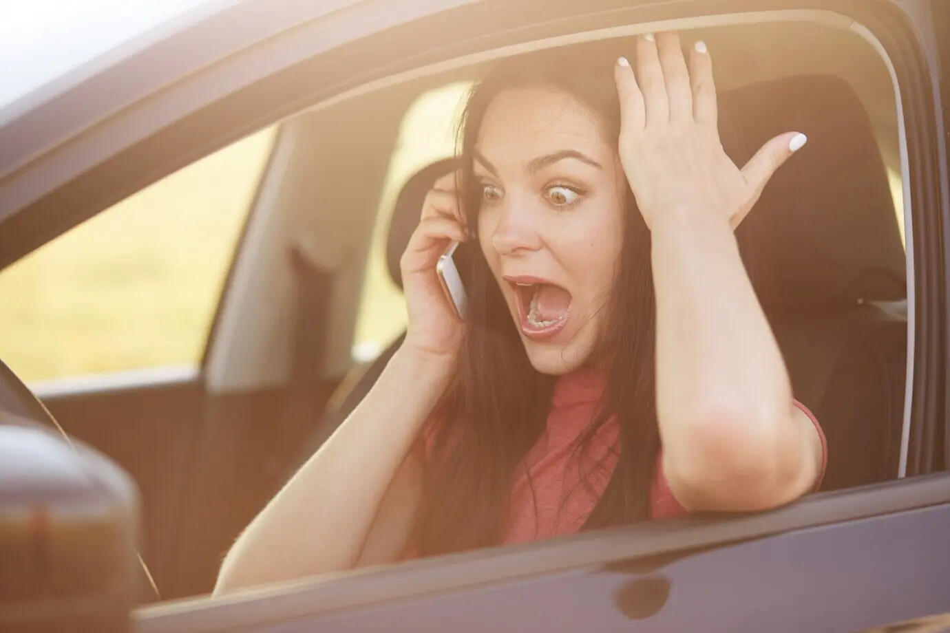 Eine Autofahrerin weiß nicht, wie sie das Auto reparieren soll, ruft ihren Ehemann per Handy an und starrt überrascht und ängstlich.